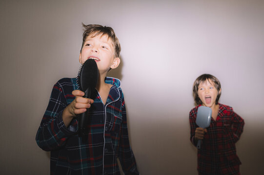 Brothers in pajamas singing with brushes and fooling around at home