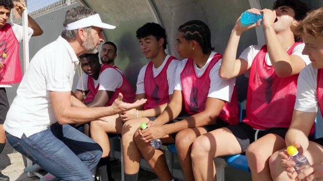 Soccer coach giving instructions to team players on bench