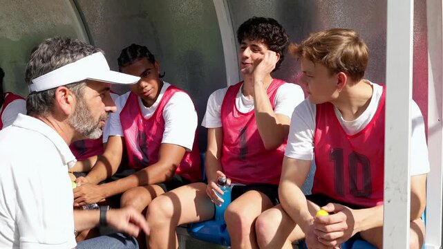 Soccer coach giving instructions to young players on the bench