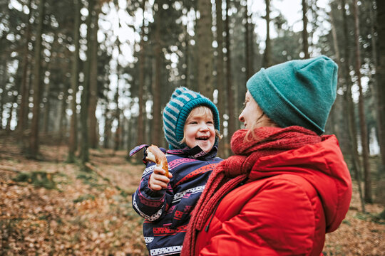 Mother carrying happy little daughter in autumnal forest
