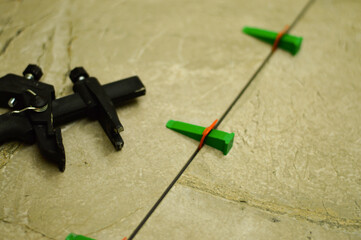 The tile is being firmly pressed into the adhesive, while the tension from the plastic leveling...