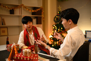 Relaxed and cheerful moment shared between colleagues during a year end party with snacks, drinks, and holiday decor