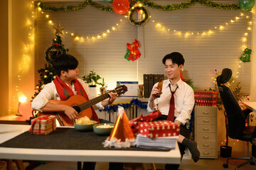 Fototapeta premium Two coworkers unwind after hours with music and drinks, surrounded by festive Christmas decor and twinkling lights