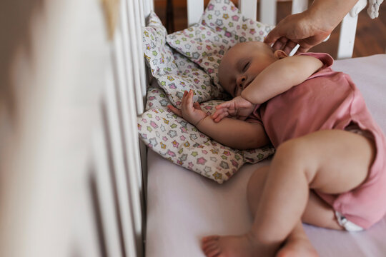 Hand of mother touching sleeping baby at home