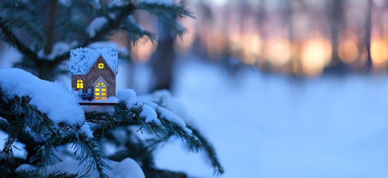 Christmas toy house on snowy tree branch, winter nature background. Christmas, new year holidays. symbol of cozy, loving family home. fairy tale atmosphere in winter season. banner. copy space