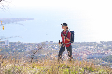 young girl with a backpack is hiking alone in nature