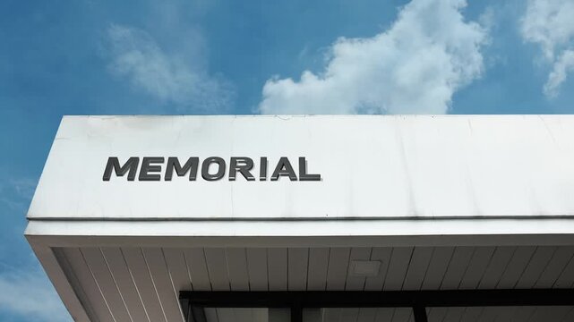 A memorial word sign prominently displayed on a dedicated public building under a clear blue sky, symbolizing remembrance, tribute, and historical significance