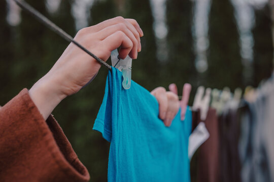 Woman putting clothespin on clothes hanging on string at back yard
