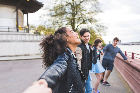 Laughing woman holding hands of friends in park