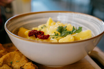 Close-up of a bowl of traditional German Swabian potato salad garnished with dried tomatoes and fresh parsley.