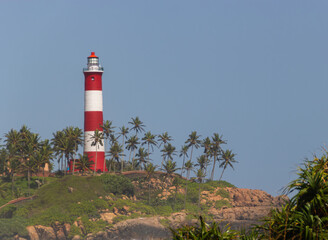 Red and White Striped Lighthouse Standing Tall on a Tropical Headland