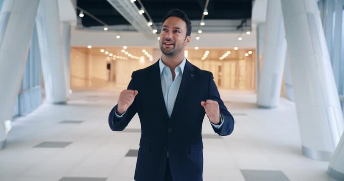 Happy enthusiastic professional man leaping in the air with elation while celebrating a major business victory in a modern corporate hallway