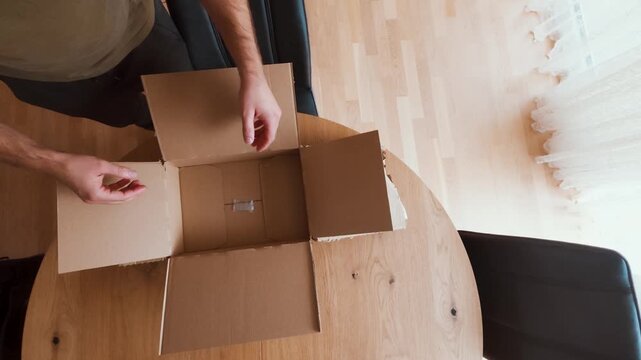 A man uses an unnecessarily large cardboard box to ship a small item. Symbolic of inefficient logistics, packaging waste, and the need for supply chain optimization or sustainability improvement.