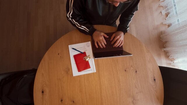 A real estate agent works on a laptop and prepares a rental or purchase contract with a red folder and key on the table. Perfect for housing, property sales, leasing, or insurance concepts.