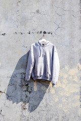 Stylish Gray Hoodie Hanging Against Distressed Urban Wall Bathed in Sunlight Creating Edgy