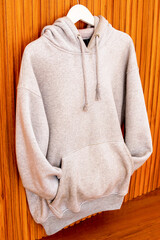 Stylish Light Gray Hoodie Hanging Against Natural Wood Background