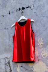 Vibrant Red Tank Top Hanging Against Textured Gray Wall Offers Modern