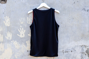 Sleek Black Tank Top Hanging Against Urban Distressed Wall Featuring Handprints