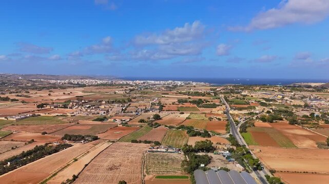 Flying above the agricultural lands of Naxxar with the St Paul's Bay and Qawra skyline with the Mediterranean Sea in the background in Malta.