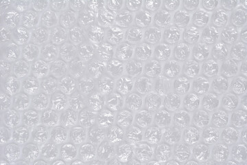 A horizontal, full-frame macro shot of clear plastic bubble wrap, creating a repetitive texture of inflated air pockets