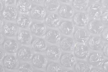 A horizontal, full-frame macro shot of clear plastic bubble wrap, creating a repetitive texture of...
