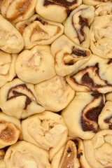 A close-up, full-frame shot of unbaked yeast dough spirals filled with melted chocolate and hazelnut paste, showing the interior swirls