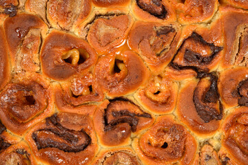 A close-up, full-frame macro shot captures the glossy, golden-brown surface and rich chocolate and hazelnut swirls of a freshly baked yeast cake