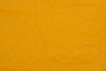A horizontal macro shot of a bright orange-yellow surface showcasing a non-uniform texture of random creases and wrinkles, resembling crumpled paper or fabric