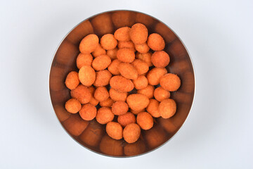 An overhead studio shot of crunchy, coated peanuts filling a stainless steel bowl, isolated on a clean white background
