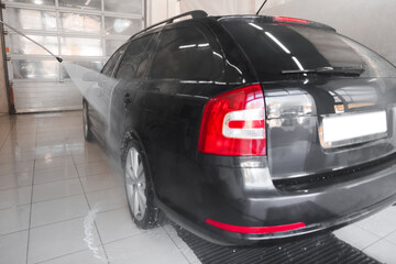 Washing auto with high pressure water jet at car wash, closeup