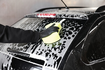 Man washing auto with sponge at car wash, closeup