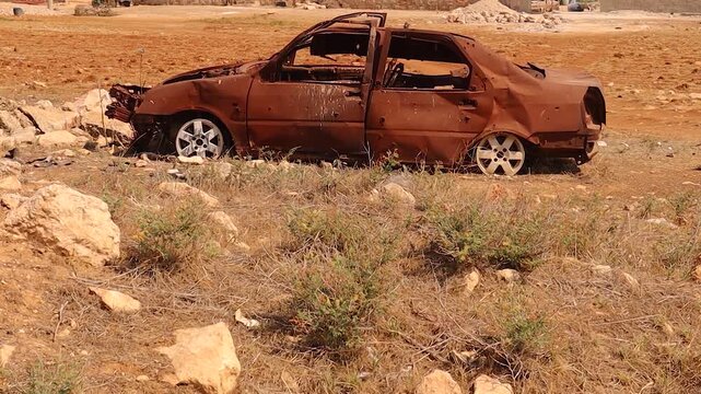 A rusted, bullet riddled car stands abandoned in Aleppo, Syria &mdash; a haunting reminder of war and destruction. Ideal for documentary films, news reports, and visual stories about conflict aftermath.