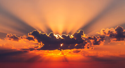 Golden sun rays shining through clouds at sunset in the sky view