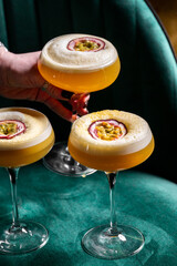 A close-up of three Pornstar Martini cocktails in coupe glasses, garnished with half a passion...