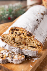 Traditional Christmas Stollen with Raisins and Powdered Sugar on wooden table
