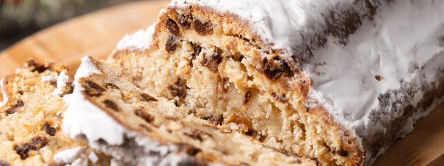Traditional Christmas Stollen with Raisins and Powdered Sugar on wooden table