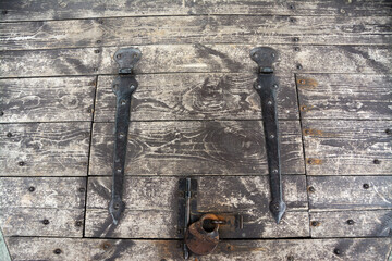 Wooden cover with rusty old iron lock and hinges.