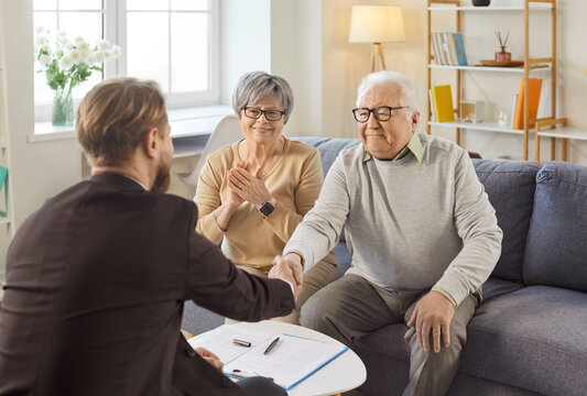 Satisfied senior couple making deal, signing contract or agreement paper, shaking hands with professional agent, financial advisor or medical insurance broker. Trust, services for older people concept - Powered by Adobe