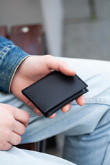 A leather purse in the hand of a young man.