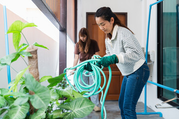 Asian woman enjoys sustainable living by gardening at home with eco friendly practices in bright lifestyle setting nurturing green plants with care and focus