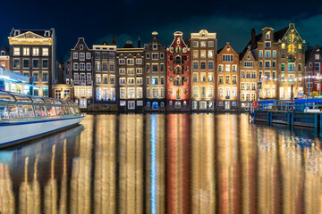 Amsterdam night. Colorful houses canal water reflection. Evening street architecture with lights in windows lanterns. Old multi colored Building.