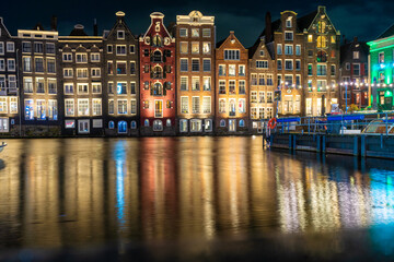 Amsterdam Netherlands night. Colorful houses canal water reflection. Sightseeing Evening street architecture with lights in windows lanterns. Old Building.