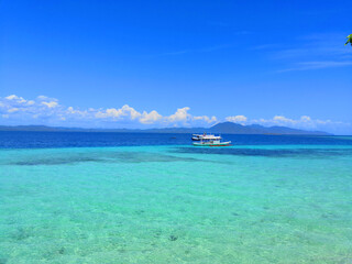 Crystal Clear Sea with Boats Under Blue Sky Coastal Background