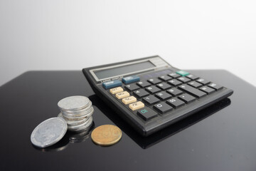 a calculator and Indonesian coins on a glossy table