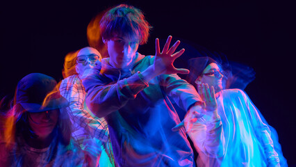 Street dancers performing with neon light motion effect. Concept of youth culture, performing arts, lifestyle promotion, and music advertising visuals showing motion.