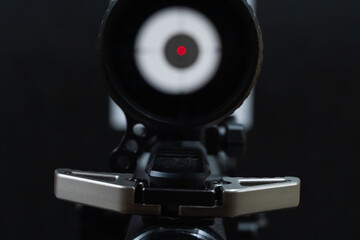Close-up point of view (POV) looking through a red dot sight on a rifle, perfectly aimed at a bullseye target.
