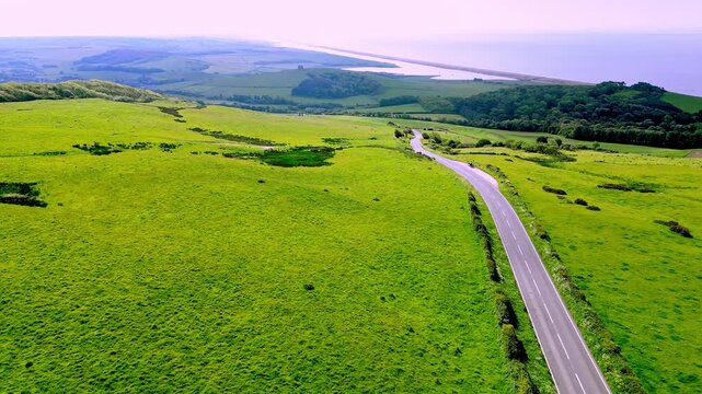 Aerial drone footage following the B3157 in West Dorset near Abbotsbury with great views of the surrounding hills and Chesil beach