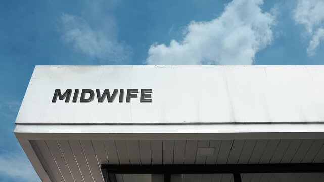 A midwife word sign prominently displayed on a healthcare building under a clear blue sky, symbolizing childbirth assistance, prenatal care, and maternal support services