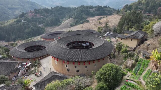 Aerial view of the historic Tulou buildings, their circular design contrasting with the surrounding terraced hills, Fujian, China.