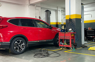 Taller mec&aacute;nico con coche rojo en revisi&oacute;n y reparaci&oacute;n